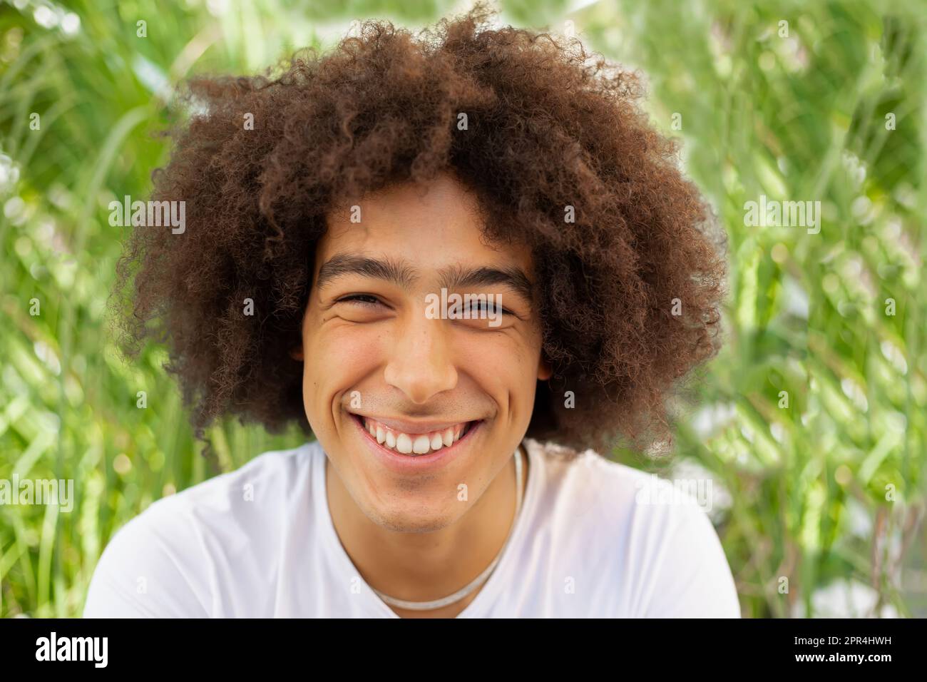 Portrait of beautiful smiling mixed race young man outdoors. Multiracial men look at camera with
