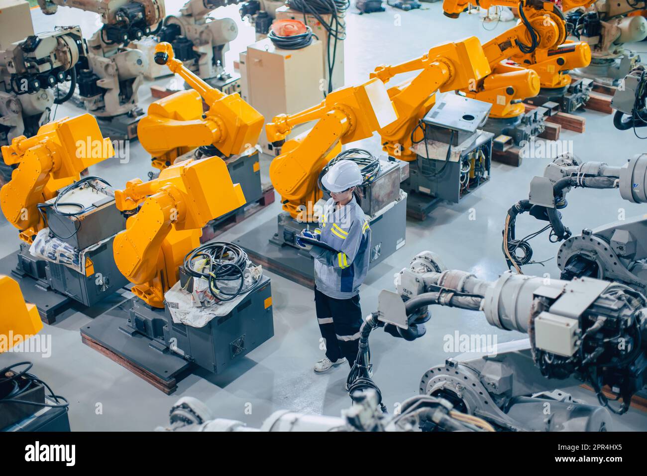 Engineer staff worker working in large machine assembly plant. employee work icounting inspection inventory of machine robot arm. Stock Photo