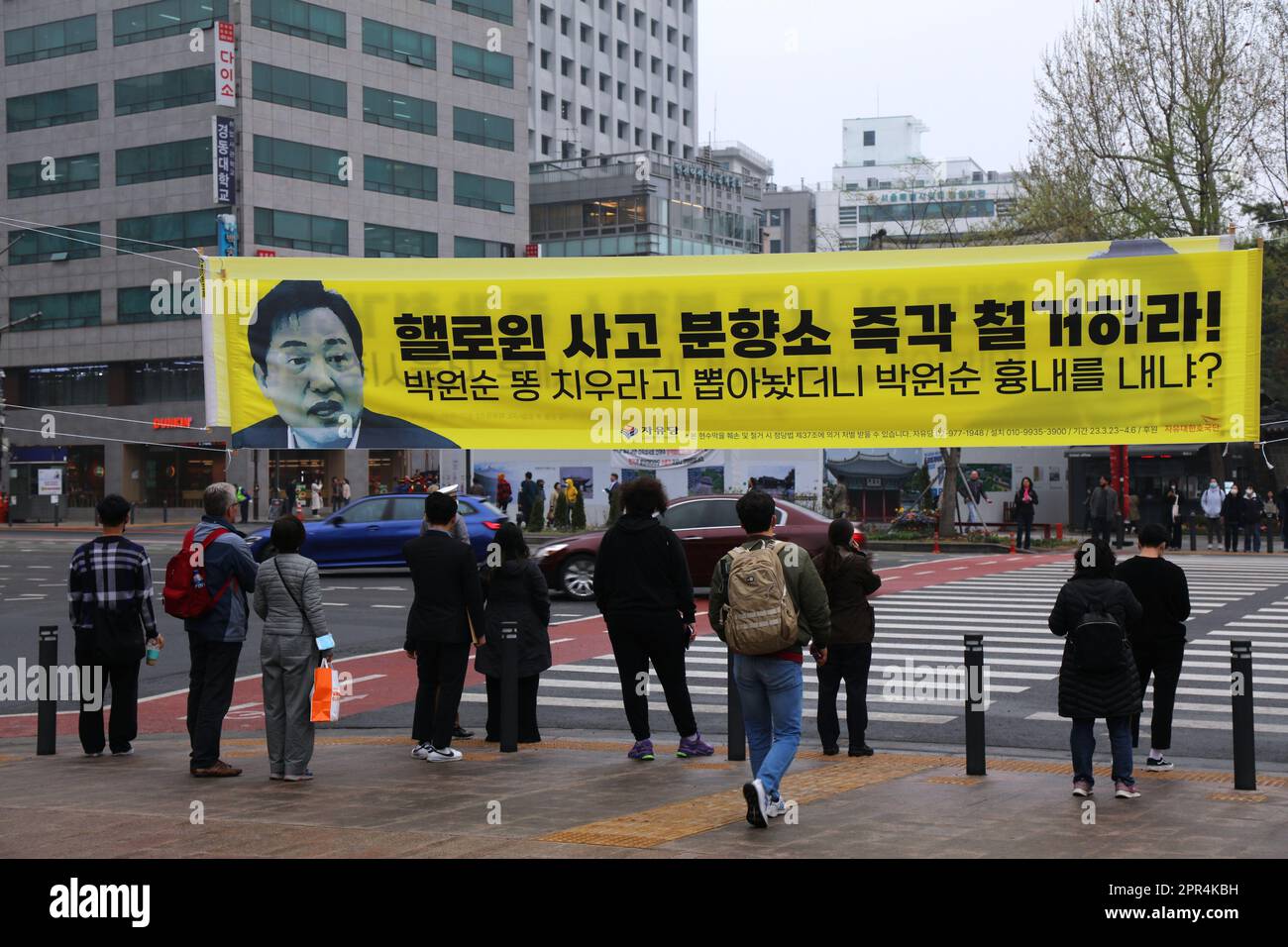 SEOUL, SOUTH KOREA - APRIL 6, 2023: People walk under campaign poster to remove incense burner set up at Seoul Plaza after Itaewon Halloween disaster. Stock Photo