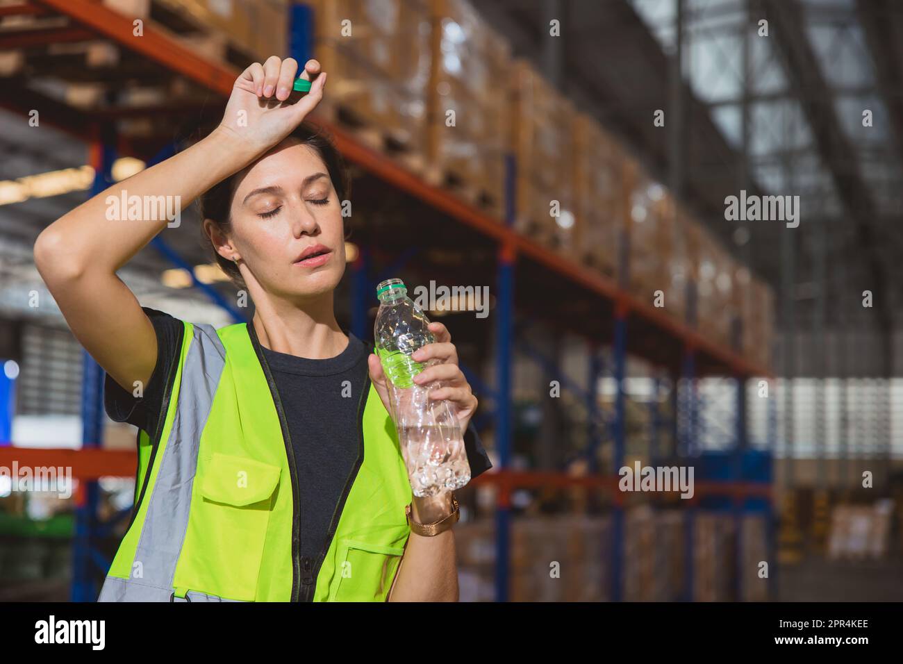 Tired stress woman staff worker sweat from hot weather in summer working in warehouse goods cargo shipping logistics industry. Stock Photo