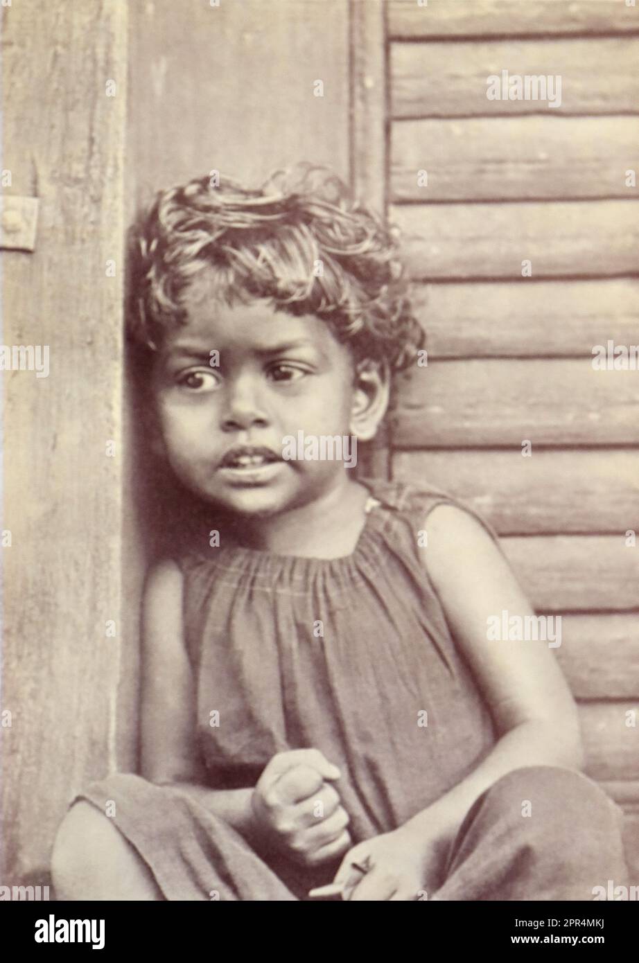 A shy girl watching the photographer with some suspicion. In the Dohnavur compound. Half-tone engraving from a photograph by Mr. Penn of Ootacamund (now known as Ooto), in the Tamil Nadu region of Southern India, c1912. The image relates to the Church of England Zenana Mission’s nursery and compound in Dohnavur, also in Tamil Nadu and about thirty miles from the southern tip of India. The compound was run by Amy Wilson-Carmichael and sought to promote Christianity among babies and children (at the time only girls, many who were victims of temple prostitution). Stock Photo