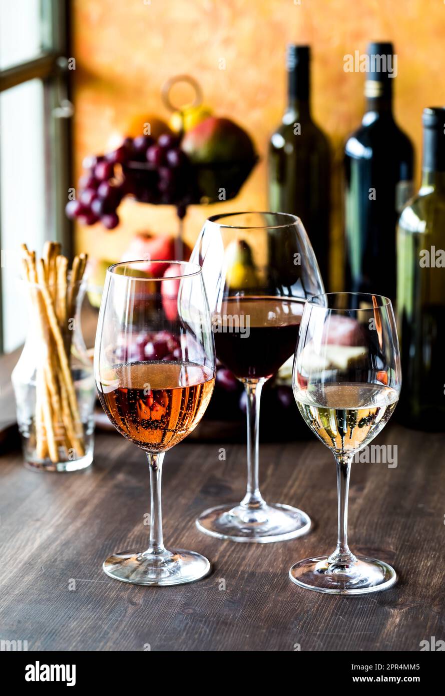 long stem wine glasses containing red, white and rose wine.  Stock Photo