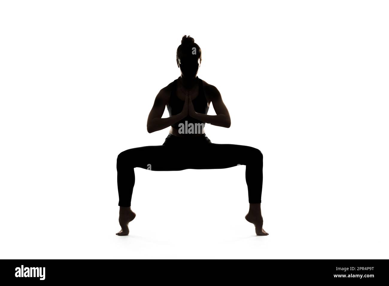 A woman is doing yoga in front of a white background. Stock Photo