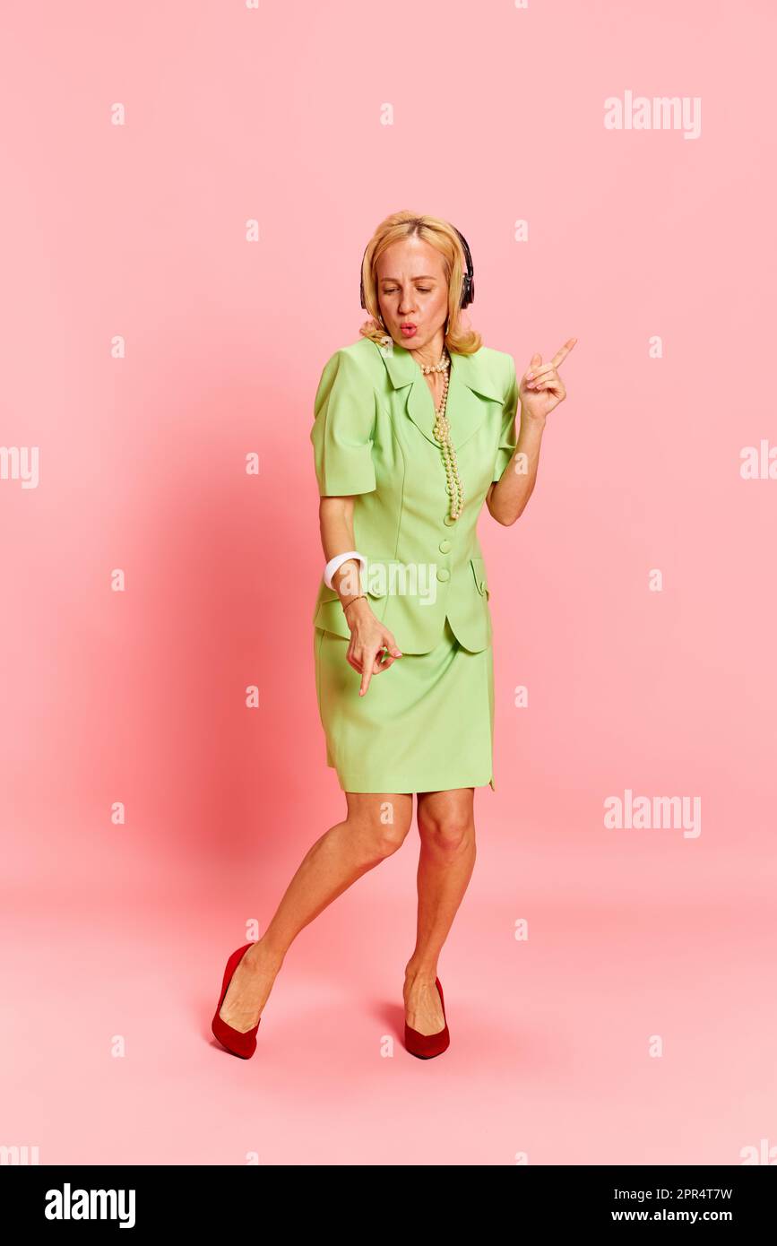Portrait of beautiful blond young woman, in retro clothes listening to ...