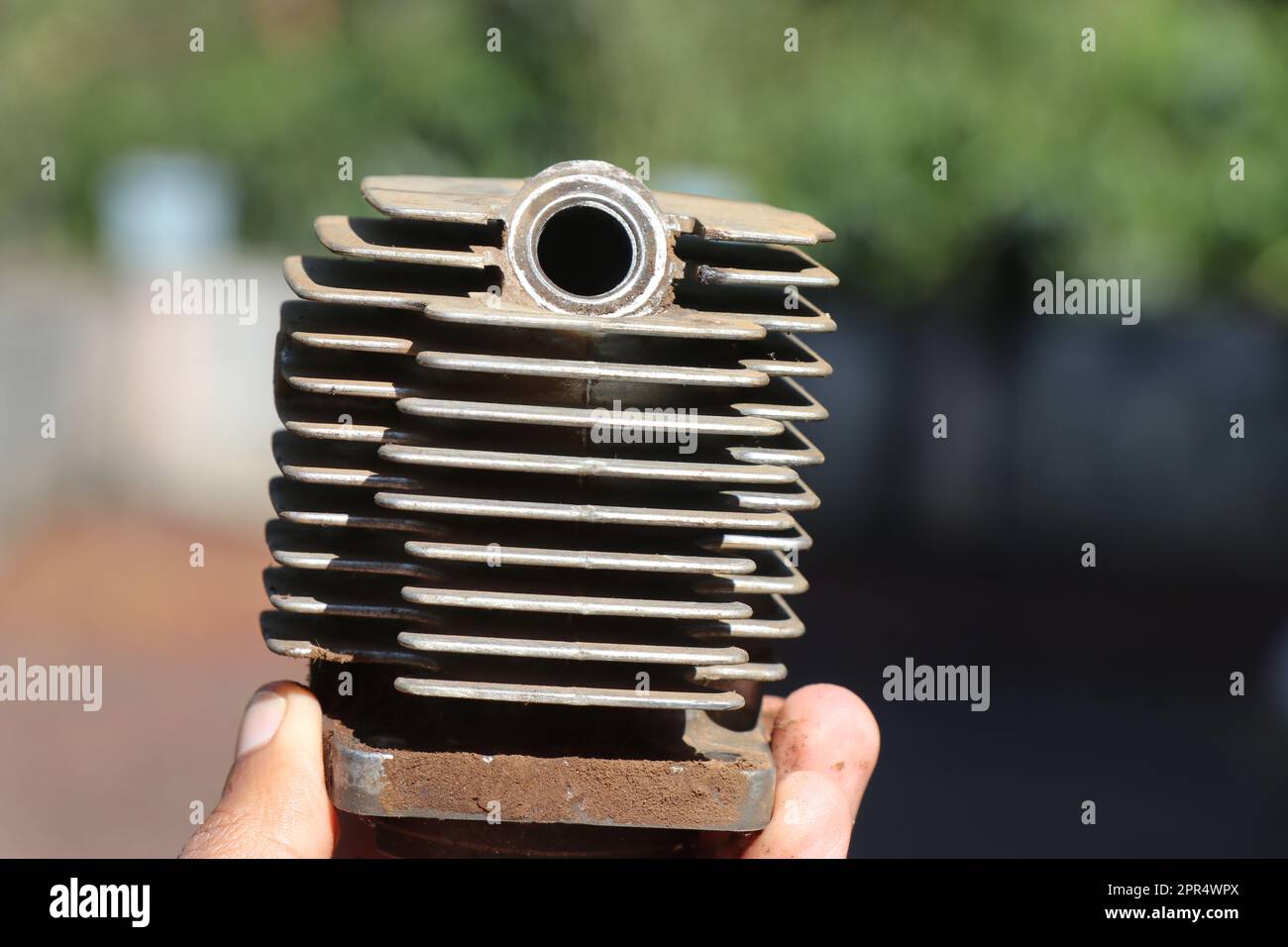 Small petrol engine cylinder head with cooling fins and a slot for adding a spark plug held in the hand Stock Photo