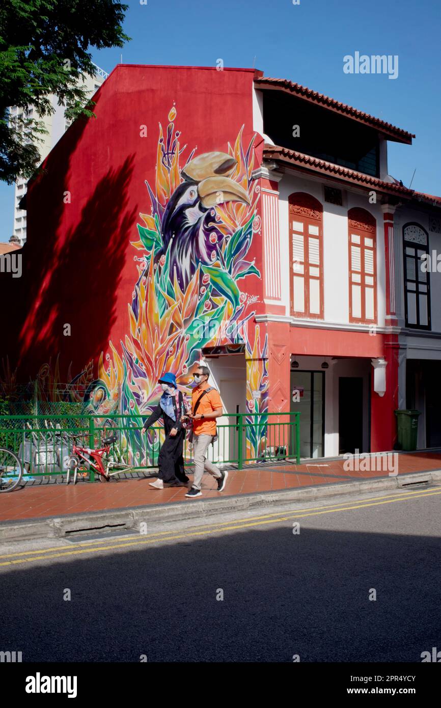 A couple passes a colorfully painted traditional Chinese shophouse with latticed windows in Syed Alwi Road, Little India, Singapore Stock Photo