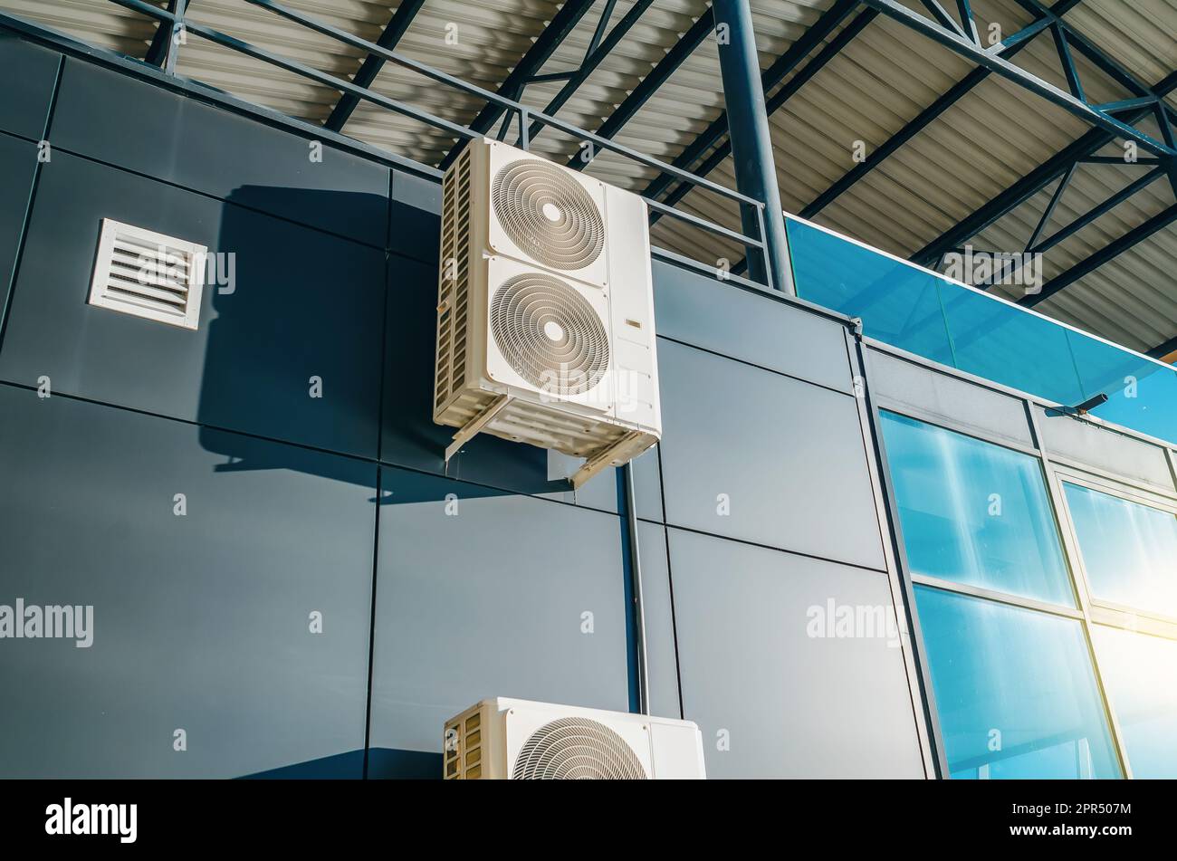 Industrial air conditioner installed on exterior metal wall of modern