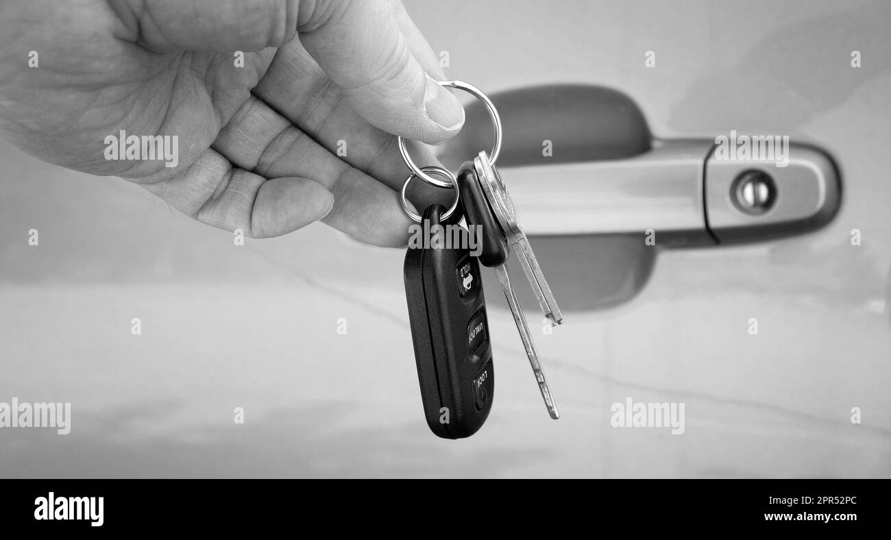 Hand holding car keys in front of grey car door Stock Photo Alamy
