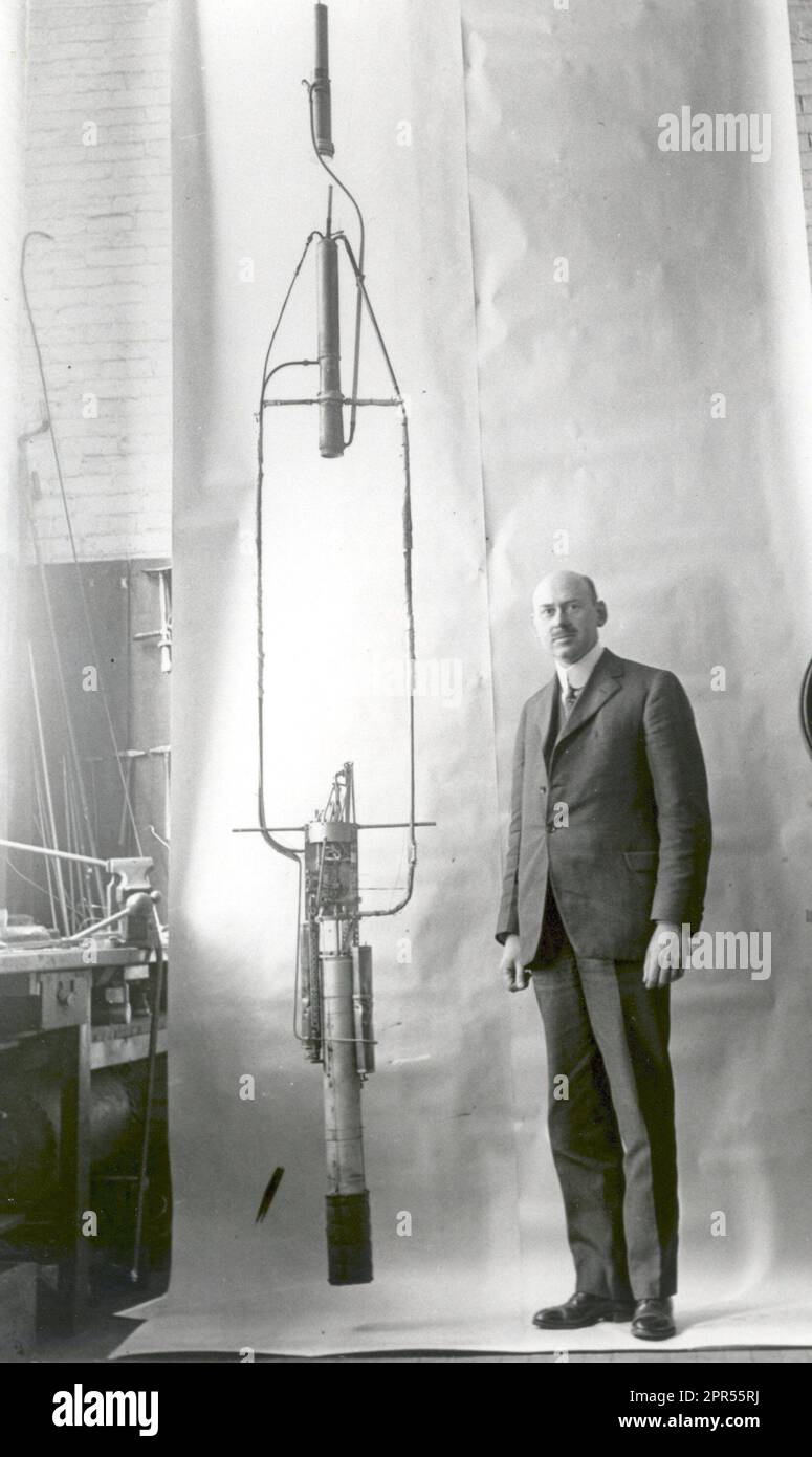 Dr. Robert H. Goddard with his complete rocket with the double- acting engine in November 1925, following more than two years of pump development based on the idea of a separate pump for each propellant. Dr. Goddard made an important change in his pump technique by combining both pumps into a single double acting unit. Though gas pressure, rather than pumps, was used on his first successful liquid-propellant rocket shot of March 16, 1926, the idea of combining both pumps into a single unit led to a successful solution of the pump problem and hence marked a significant advance. Stock Photo