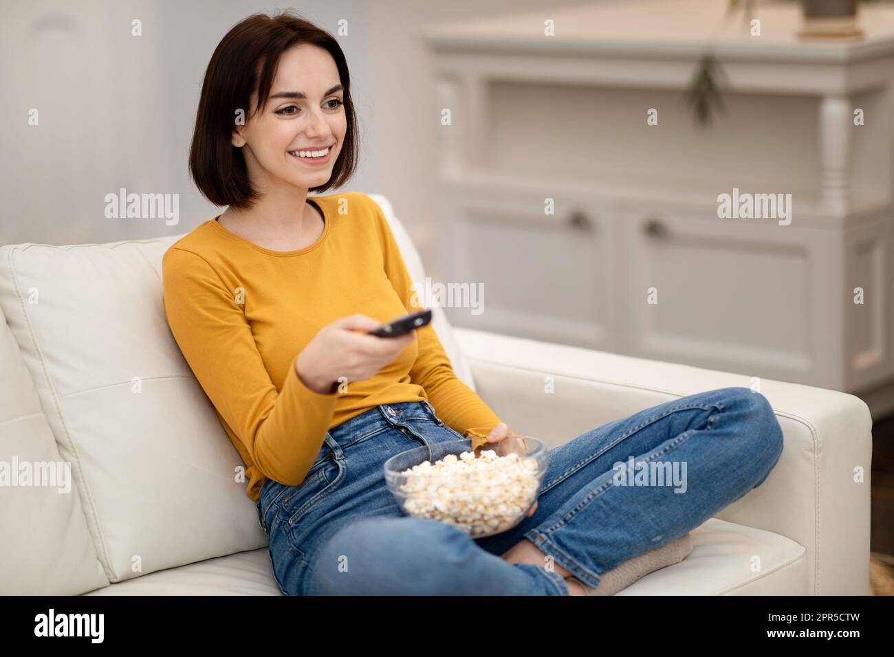 Reaxed pretty young woman relaxing at home, watching TV Stock Photo