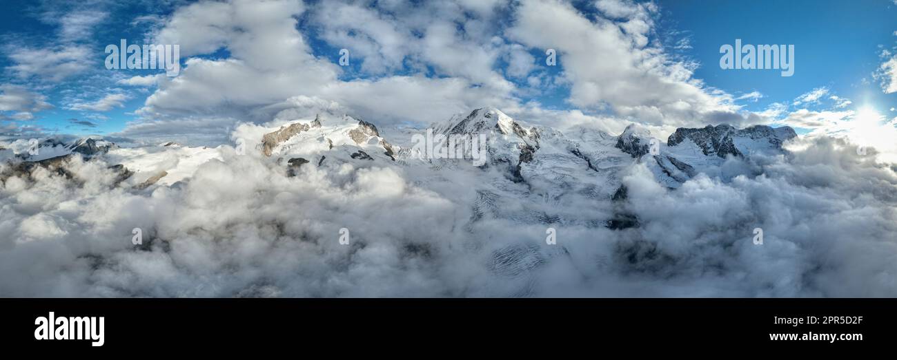 Aerial panoramic view of snowcapped Monte Rosa, Lyskamm, Pollux, Castor, Breithorn in a sea of clouds, Zermatt, Valais, Switzerland Stock Photo