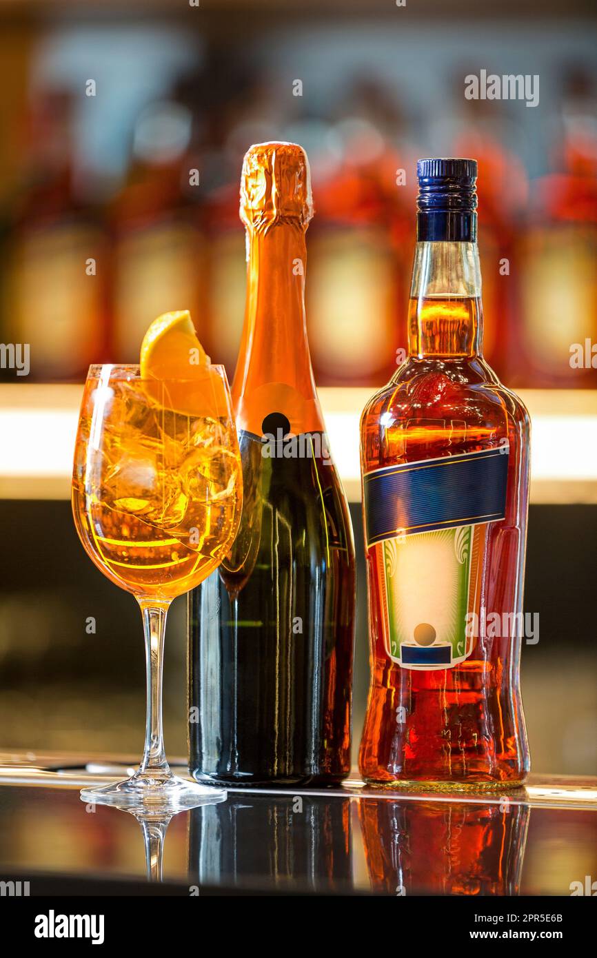 A bottle of liquor next to a glass of orange juice with ice and a bottle of champagne Stock