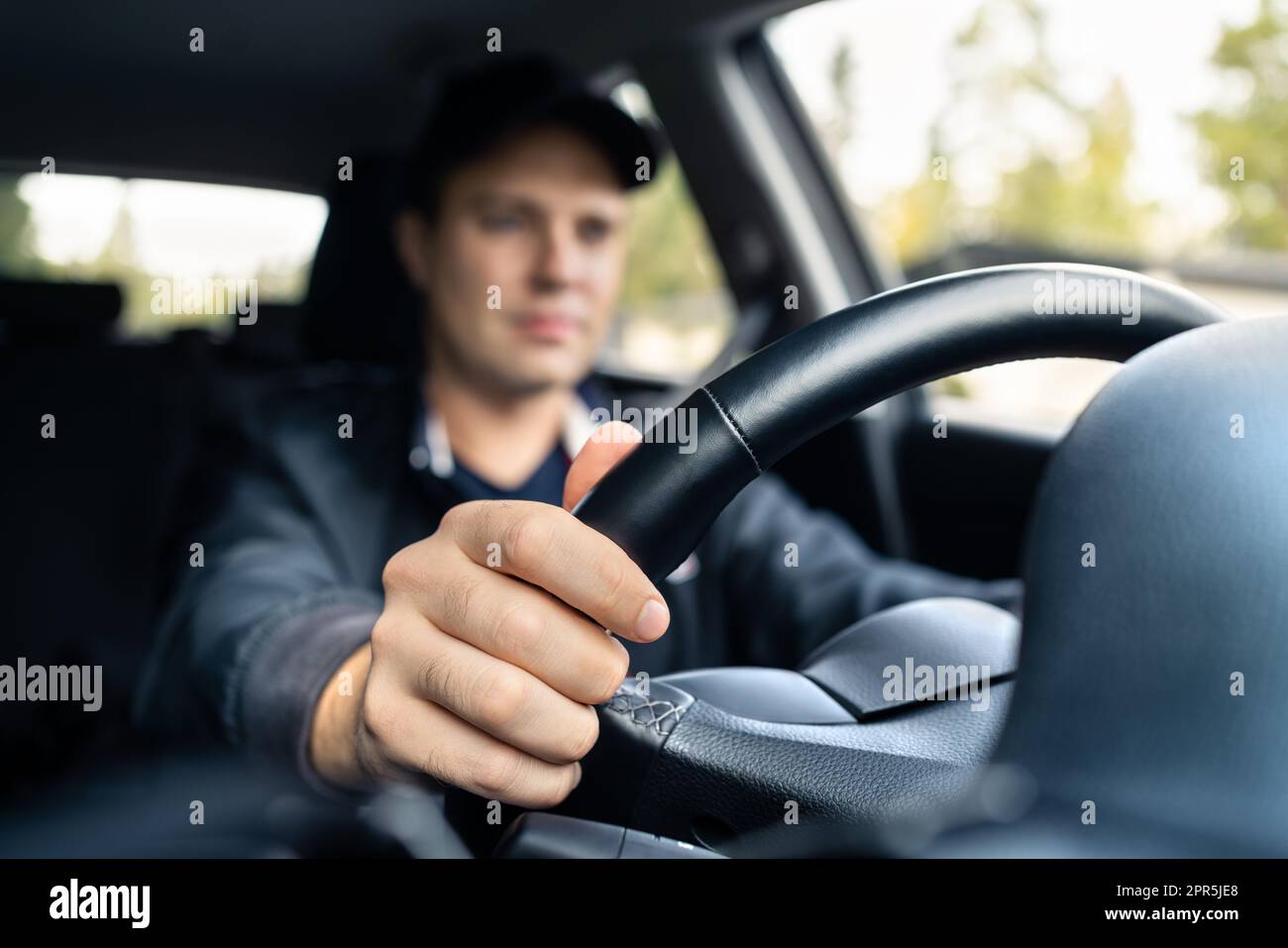 Man driving car. Driver in summer. Taxi cab chauffeur. Traffic insurance or commute concept. Happy young person working in vehicle dealership. Stock Photo