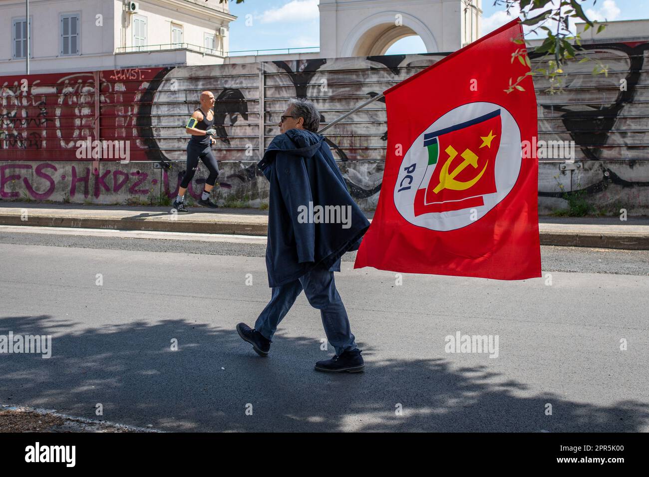 A man seen walking with the red flag of the Italian Communist Party during the demonstration. About 10 thousand demonstrators took part during the parade organized by the ANPI (National Association of Partisans of Italy) in Rome on the occasion of the 78th anniversary of the Liberation from Nazi-fascism. Starting from Largo Bompiani, they crossed the neighborhoods of Tor Marancia, Garbatella and Ostiense, until they arrived at Porta San Paolo. The demonstration ended in Piazzale Ostiense with speeches by political figures, trade unions and the testimonies of those who were partisans during the Stock Photo