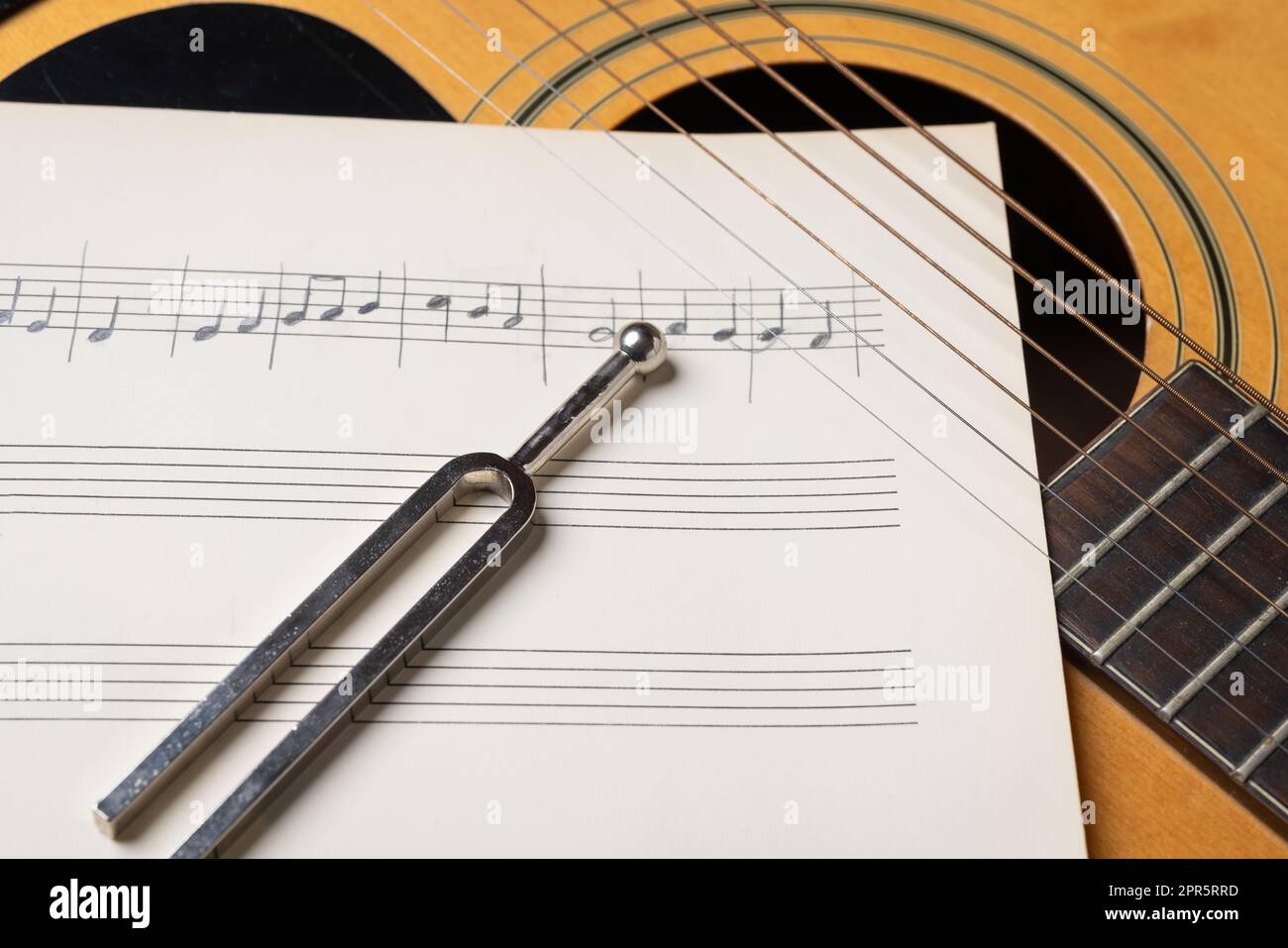 acoustic guitar tuning music sheets and tuning fork close up Stock Photo