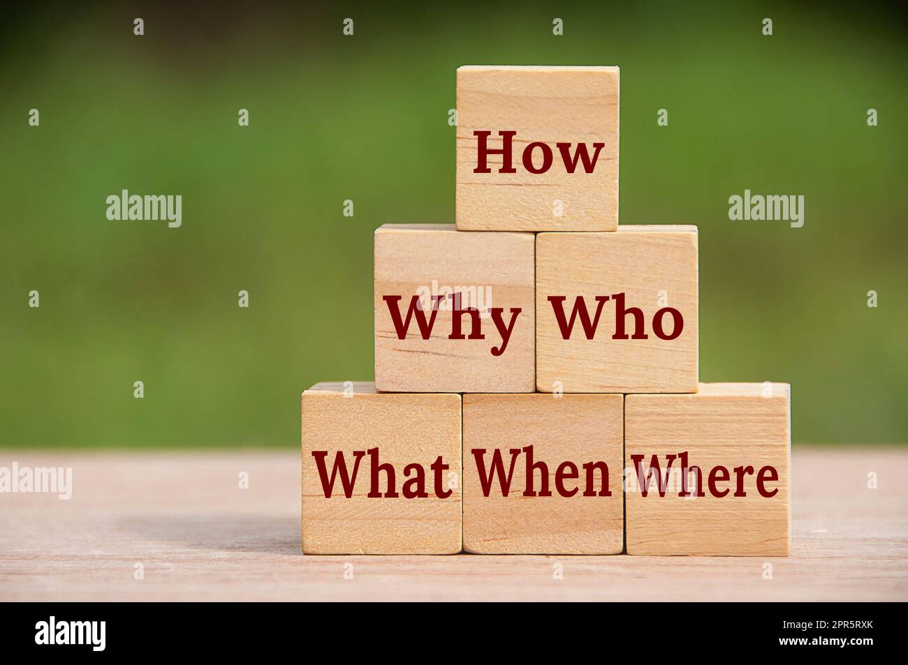 How, why, who, what, when and where text on wooden block with blurred nature background. Stock Photo