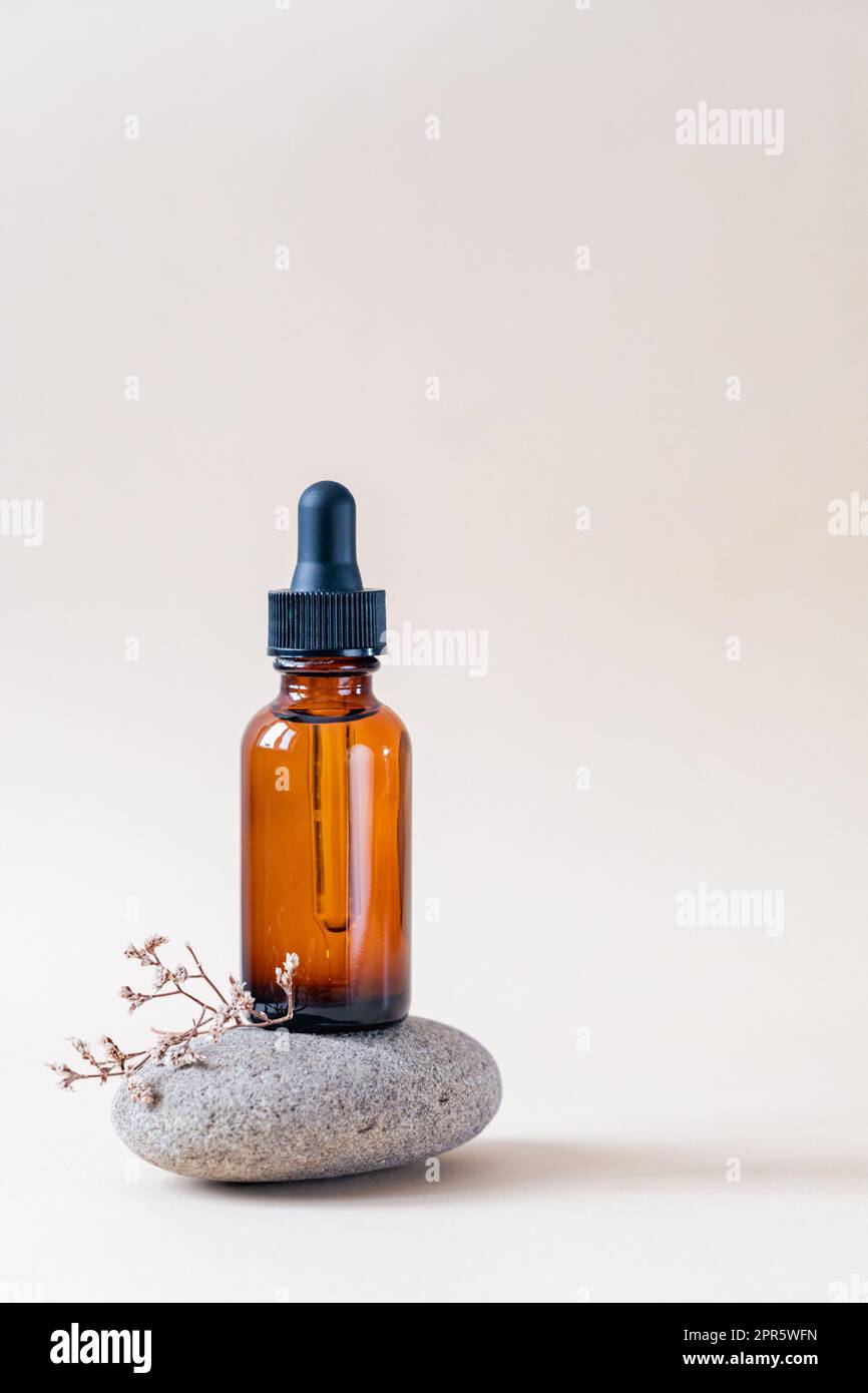 Amber glass dropper bottle with black lid on a podium on stones. Skincare products , natural cosmetic. Beauty concept for face and body care Stock Photo