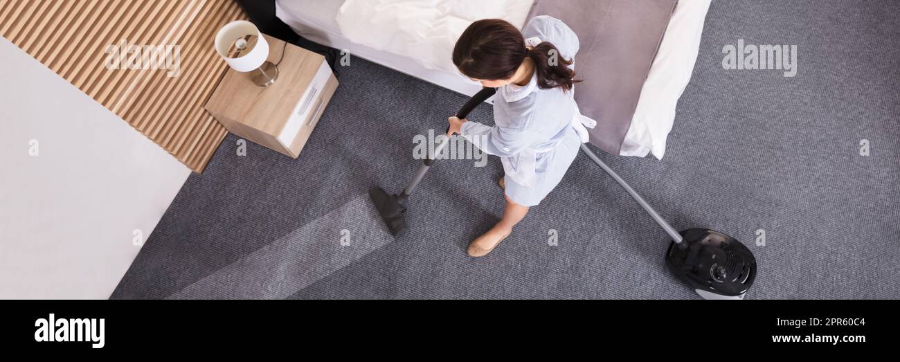 Female Janitor Cleaning Carpet With Vacuum Cleaner Stock Photo