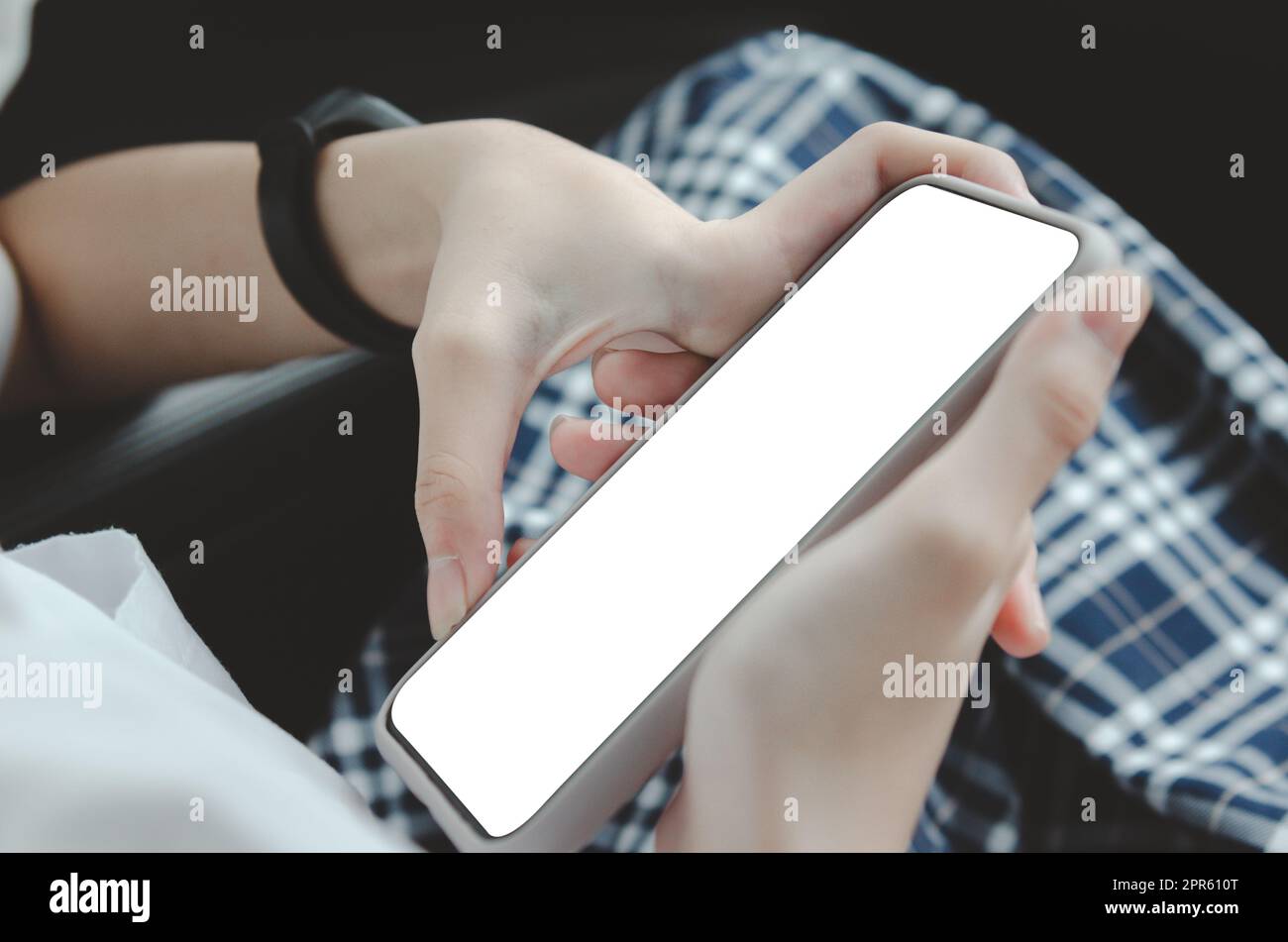 woman hand holding a mobile phone in the car cabin.Blank with white screen.Mock up smart phone interior car. Stock Photo