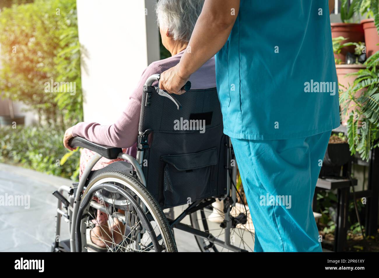 Caregiver help and care Asian senior or elderly old lady woman patient sitting in wheelchair on ramp at nursing hospital, healthy strong medical concept Stock Photo