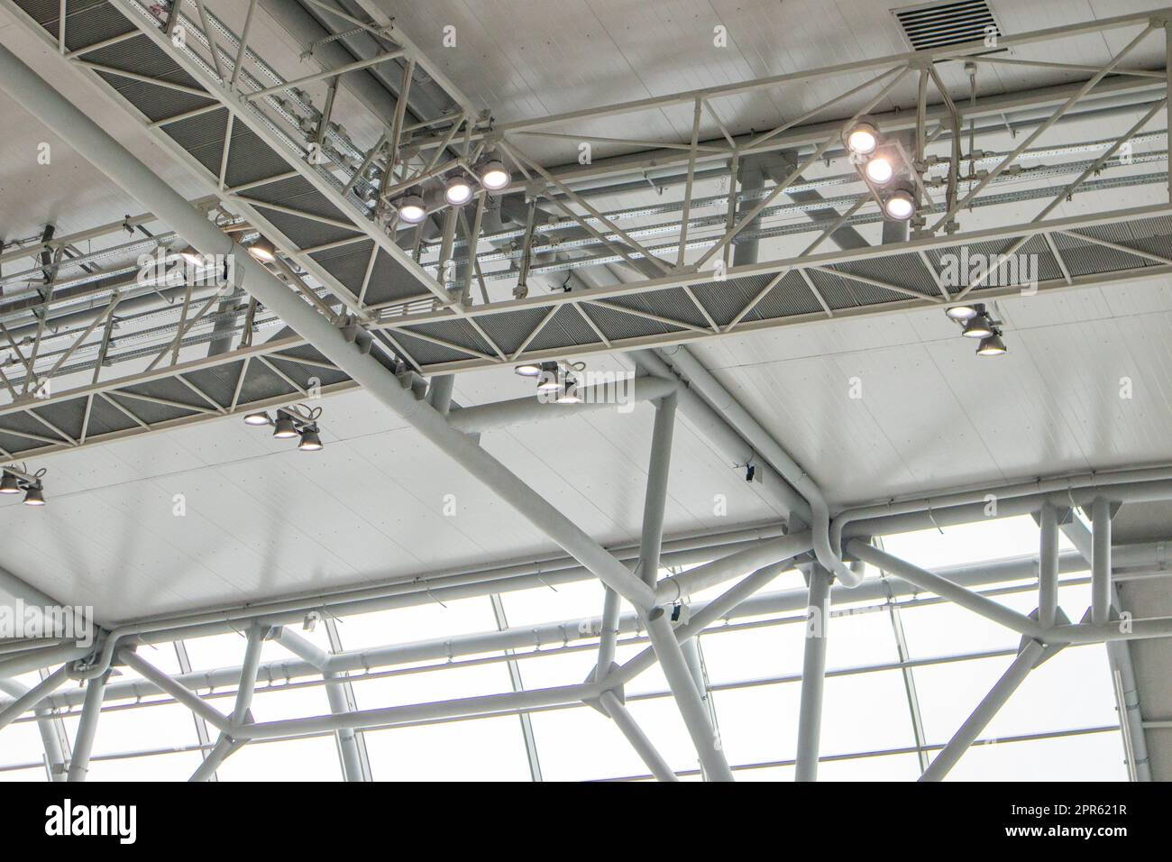 Ceiling with bright lighting in a modern warehouse, shopping center building, airport or other commercial real estate object. Directional LED lights on rails under the ceiling Stock Photo