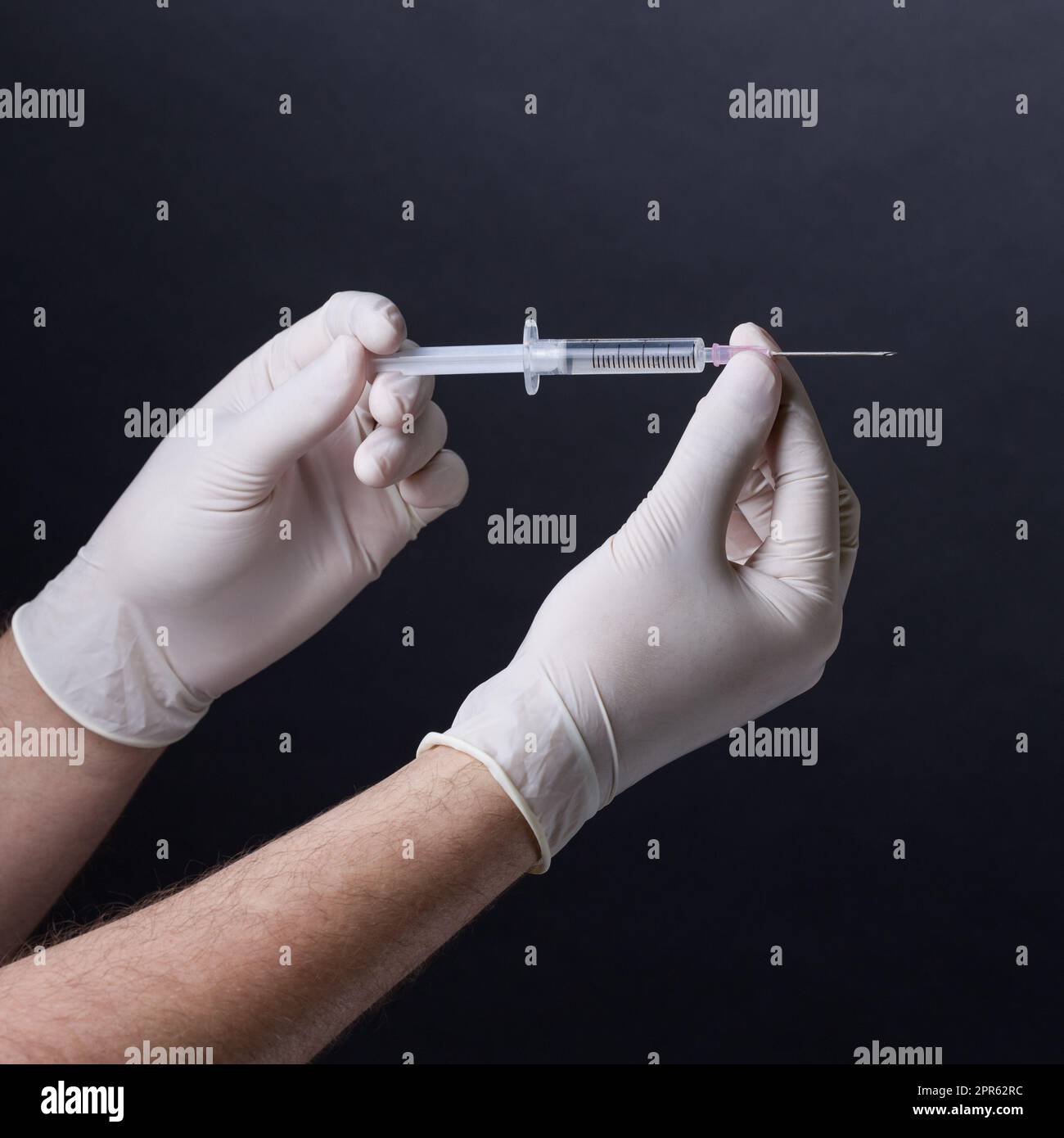 Gloved hands holding a syringe Stock Photo