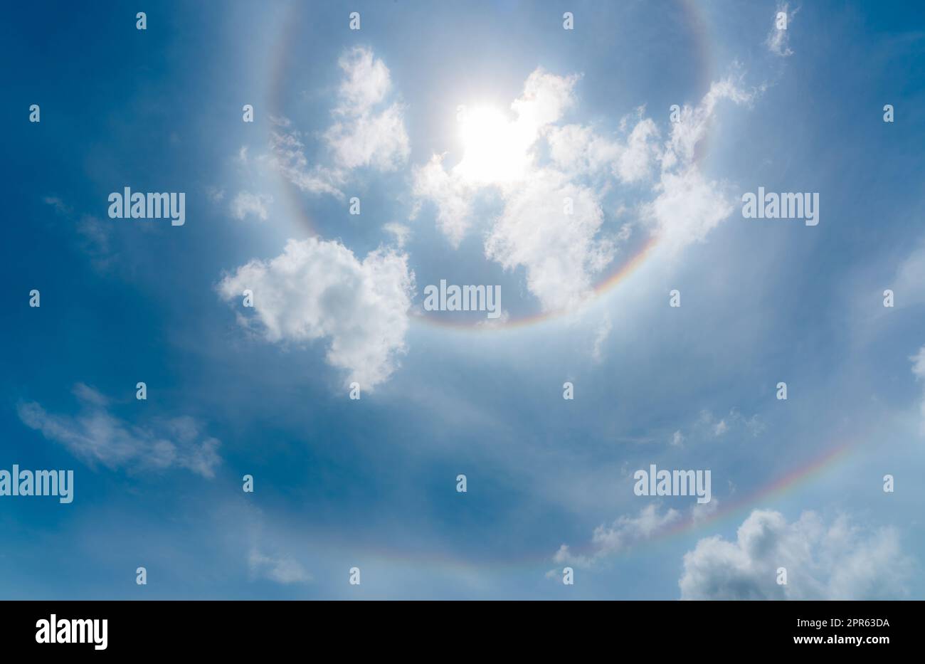 Sun Halo or a rainbow-colored ring around the sun. Sunny sky with sun halo. Optical phenomenon produced by light. Cirrus or cirrostratus clouds in the troposphere with light refraction and reflection. Stock Photo