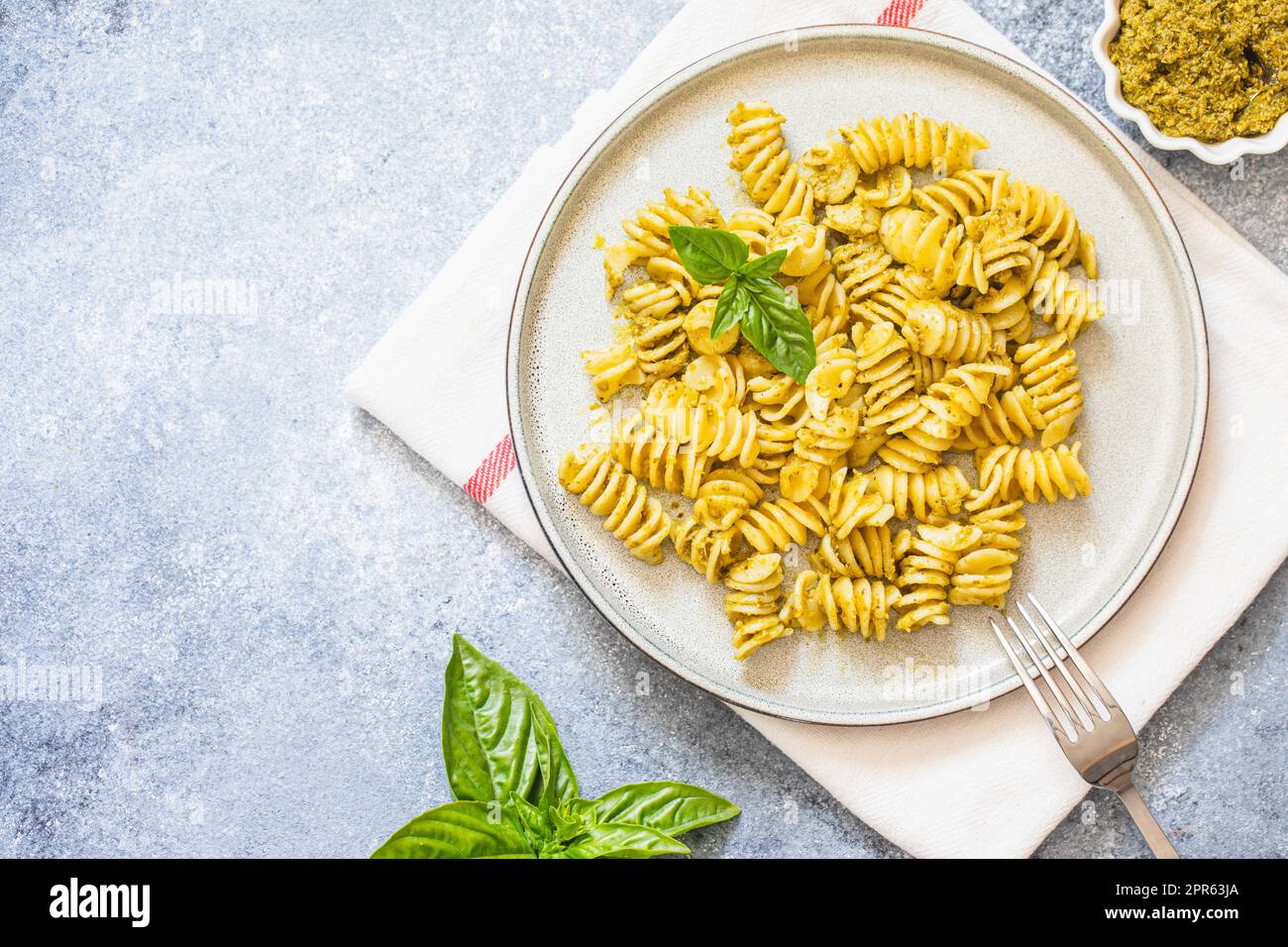 fusili pasta with basil pesto and herbs, italian cuisine, gray stone background. Home made food. Stock Photo