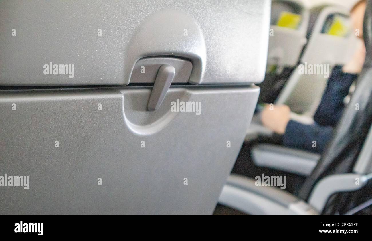 Selective focus on a closed table, a table for food in the cabin, a blurred background of passengers in the background of the interior, the concept of convenient flights and travel Stock Photo