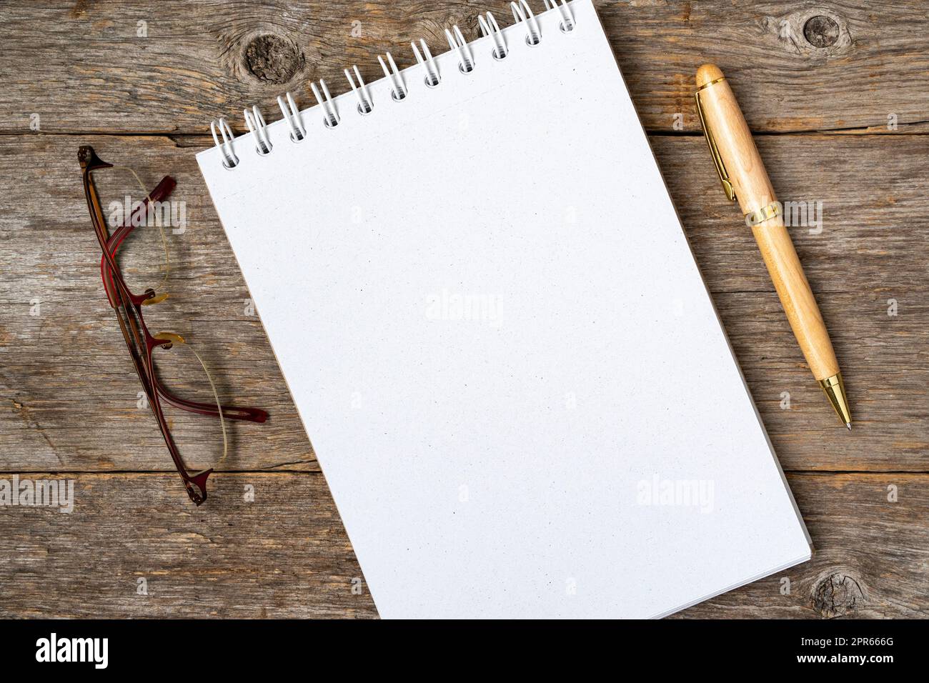 Blank spiral notebook, pen and glasses on a wooden table Stock Photo