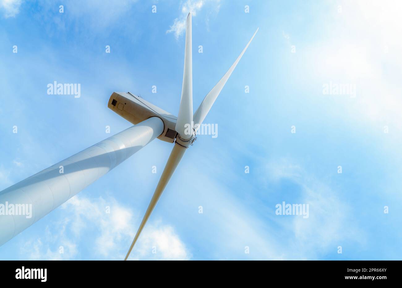 Wind energy. Wind power. Sustainable, renewable energy. Wind turbines generate electricity. Windmill against blue sky and sun light. Green technology. Renewable resource. Sustainable development. Stock Photo
