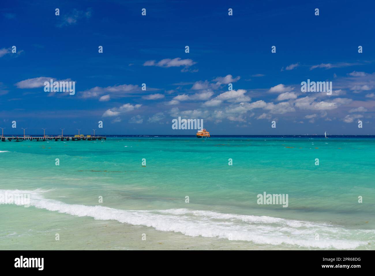 Orange ferry in azure ocean with swimming people in Playa del Carmen