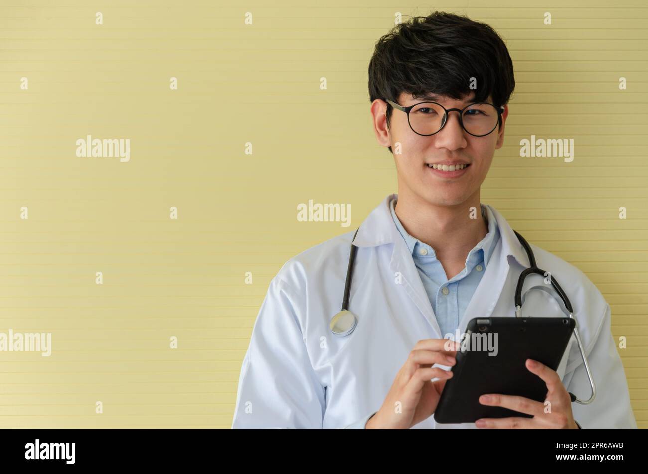 Young doctor in white uniform using tablet PC and looking at camera Stock Photo