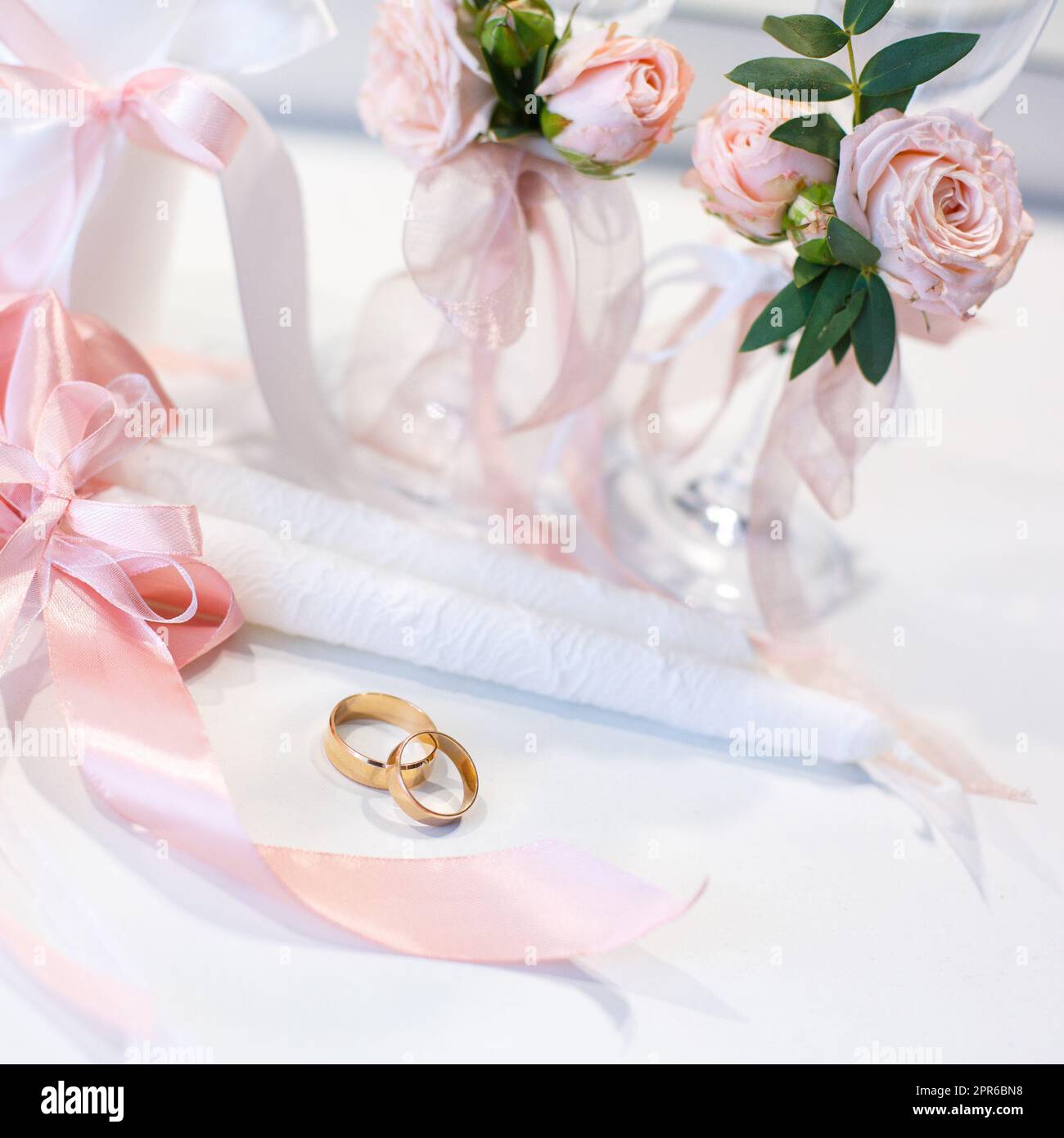 Gold wedding rings lie on the table near the wedding candles. Stock Photo