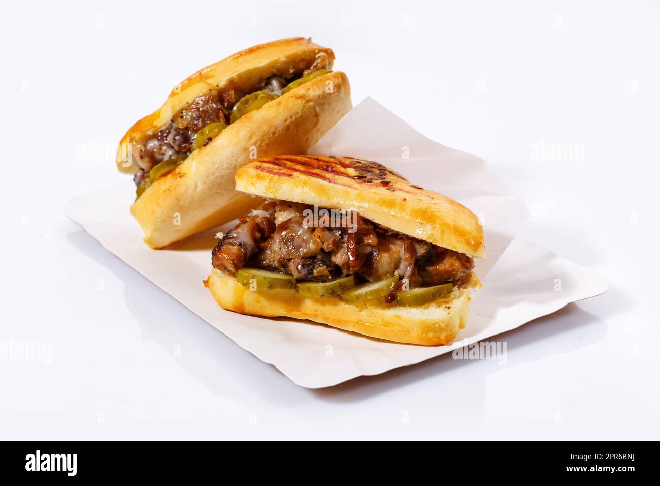 Street food sandwiches with meat, pickled cucumbers on a white plate