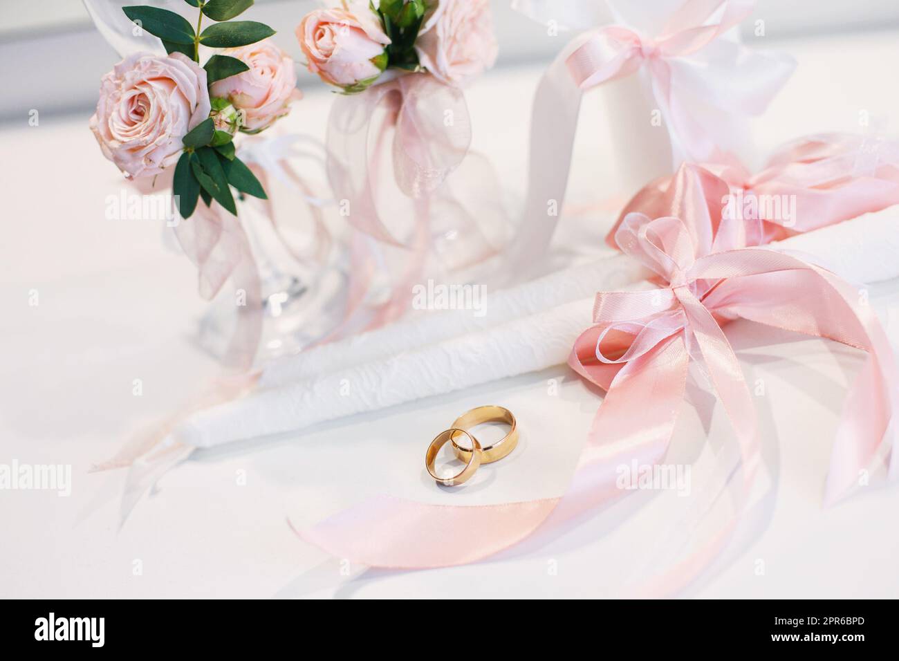 Gold wedding rings lie on the table near the wedding candles. Stock Photo