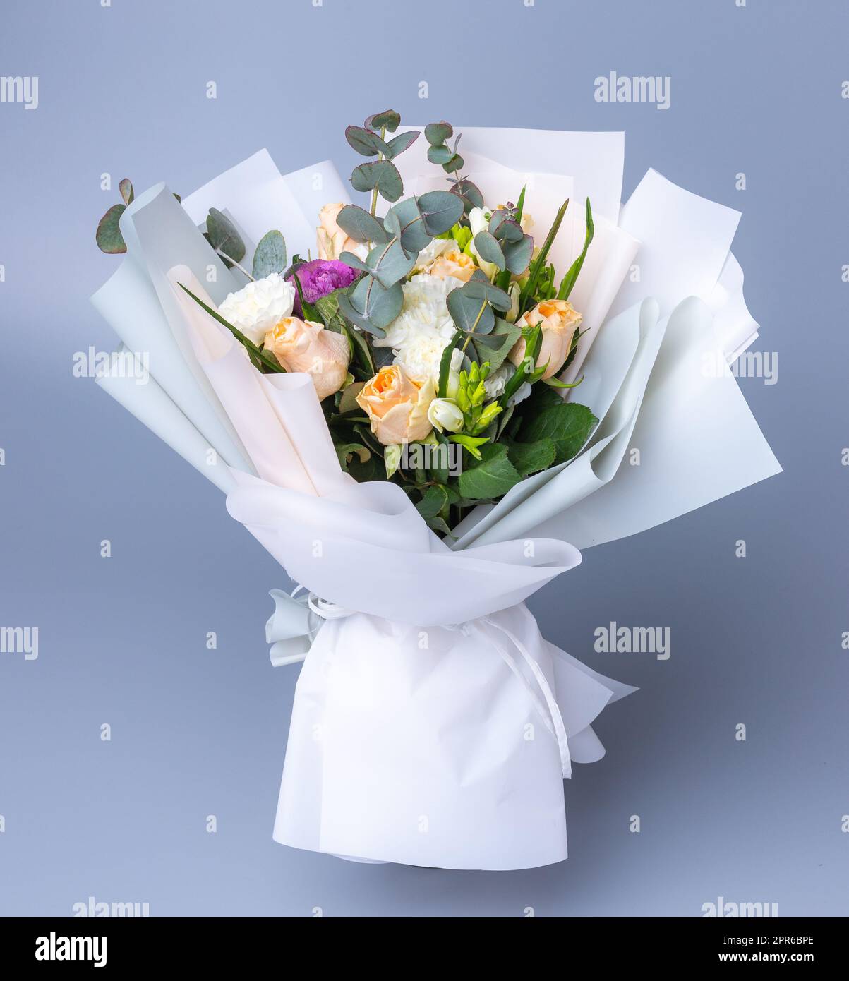 Delicate romantic bouquet of flowers wrapped in white paper. Stock Photo