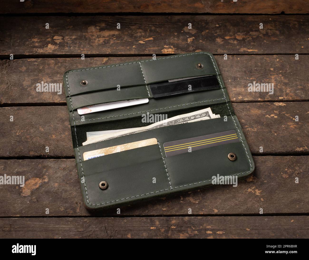 Leather green wallet with money and credit cards on old wooden background Stock Photo