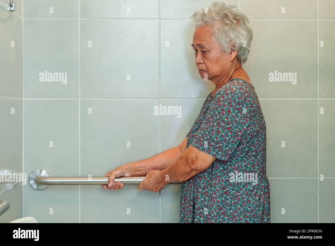 Asian elderly old woman patient use toilet support rail in bathroom, handrail safety grab bar, security in nursing hospital. Stock Photo