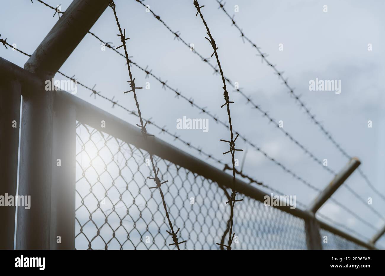 Prison security fence. Border fence. Barbed wire security fence. Razor wire jail fence. Boundary security wall. Prison for arrest of criminals or terrorists. Private area. Military zone concept. Stock Photo