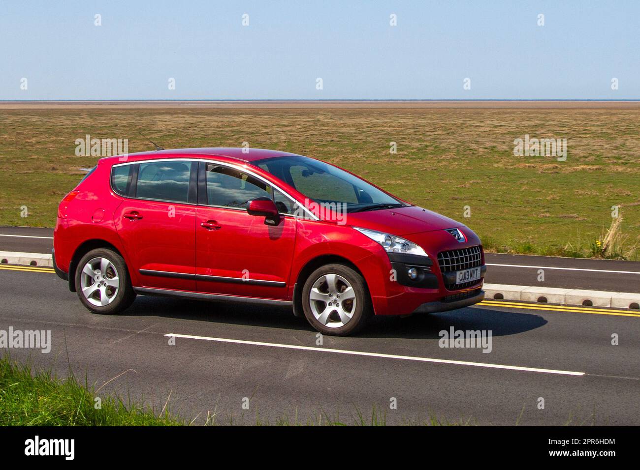 Side View of 2013 Peugeot 3008 Active Hdi 115 Car Red SUV Diesel 1560 cc; travelling on the seafront Marine Drive, Southport, UK Stock Photo