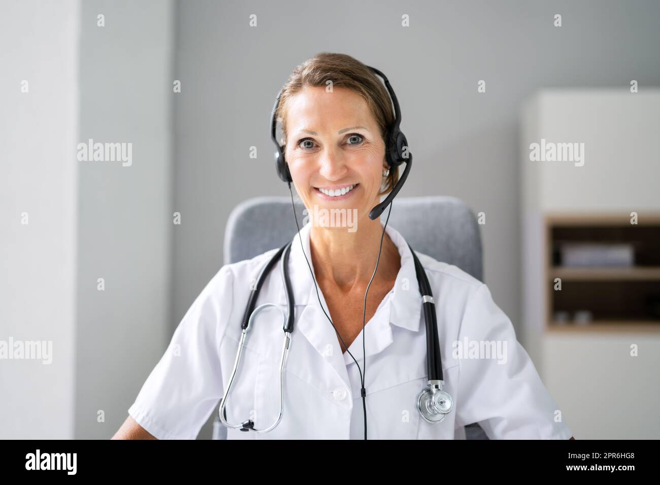 Confident Receptionist Using Headset In Hospital Stock Photo