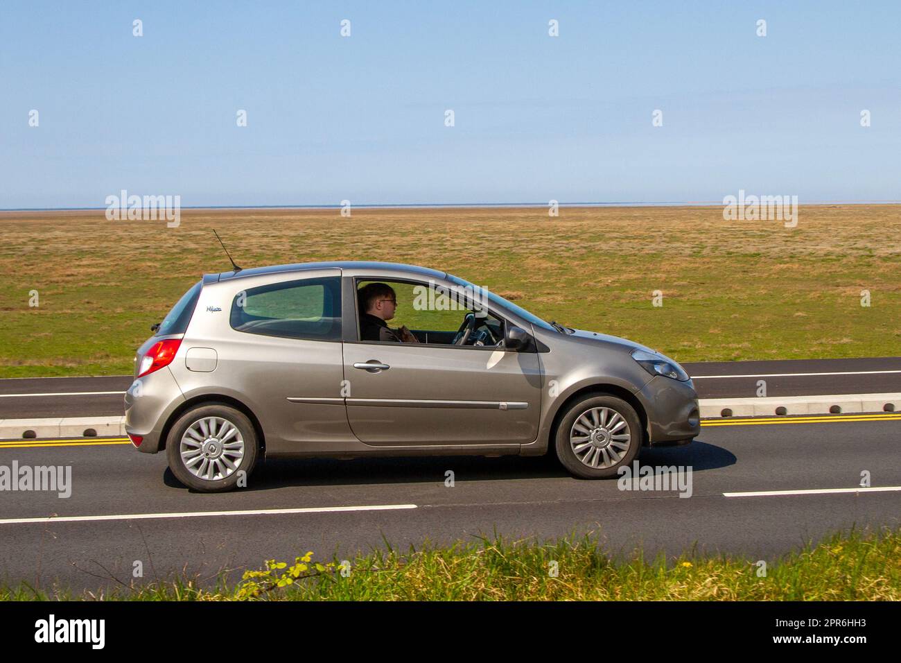 Side View of 2011 Renault Clio I-Music Beige Car Hatchback Petrol 1149 cc; travelling on the seafront Marine Drive, Southport, UK Stock Photo