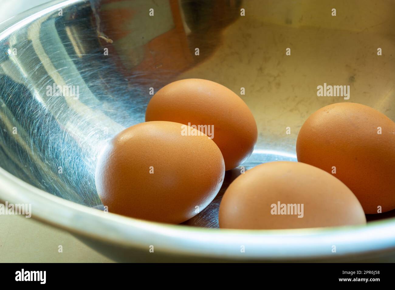 Raw eggs in shells in a silver bowl Stock Photo