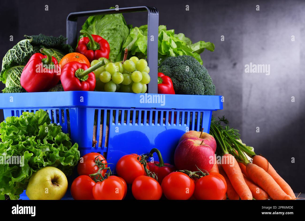 Fresh organic fruits and vegetables in plastic shopping basket Stock