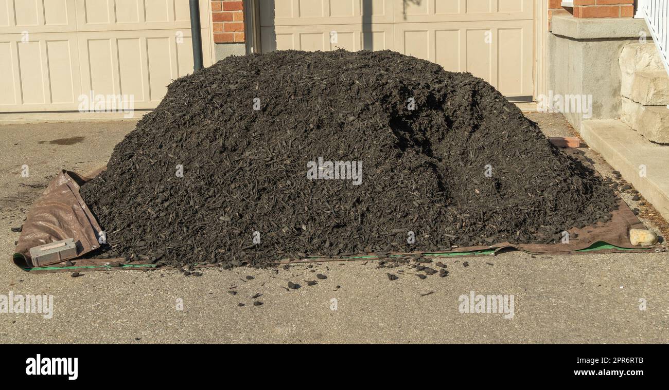 A pile of black mulch for plants and paths near the flower bed, poured