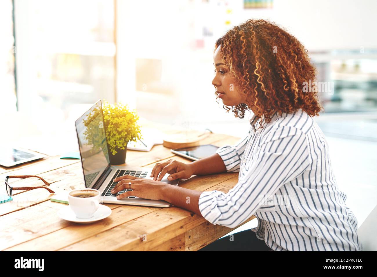 Shes the best in the creative biz. Cropped shot of an attractive young woman using her laptop on a wooden table. Stock Photo