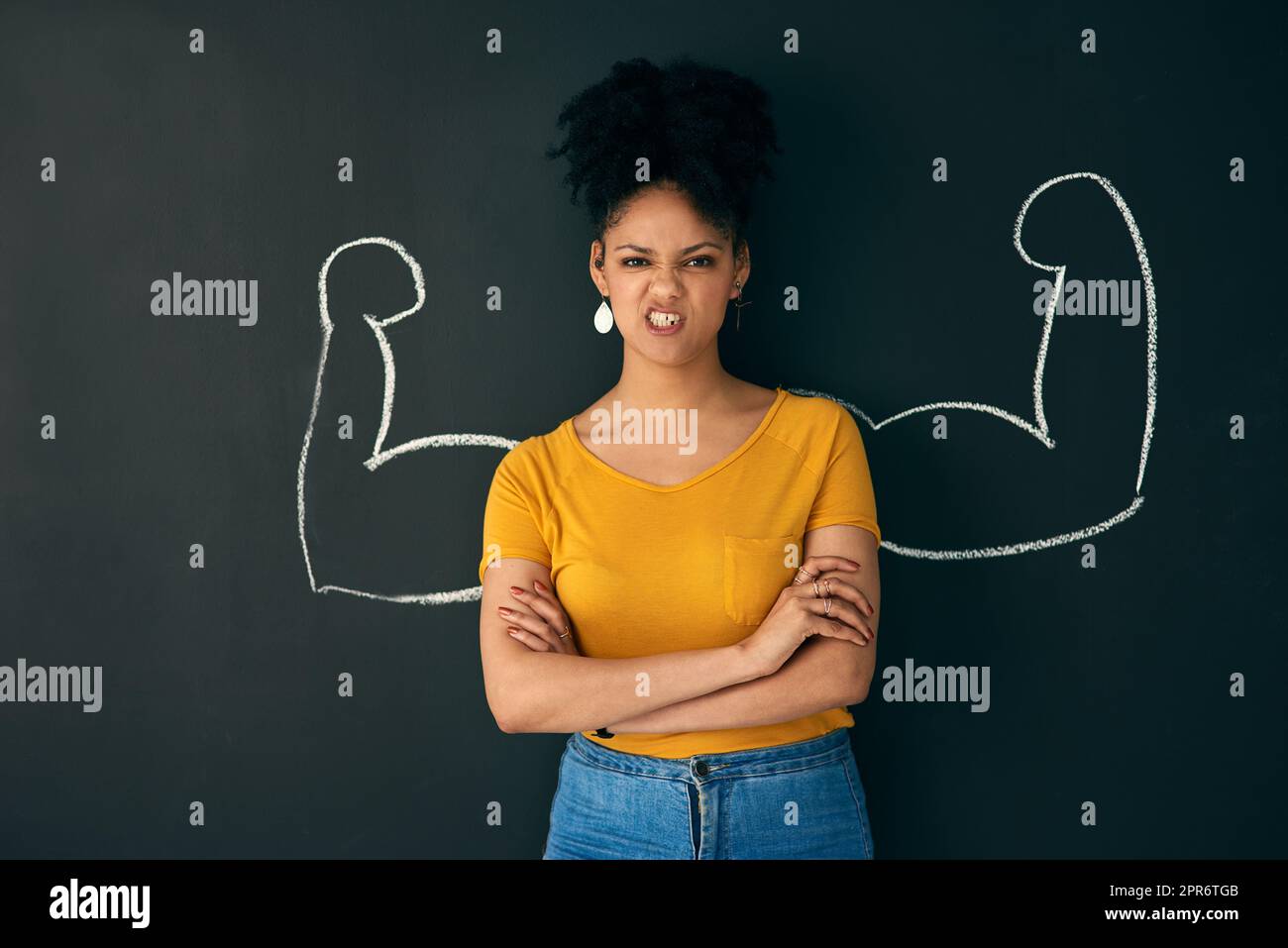 Sometimes being strong is the only choice you have. Shot of a woman posing with a chalk illustration of flexing muscles against a dark background. Stock Photo