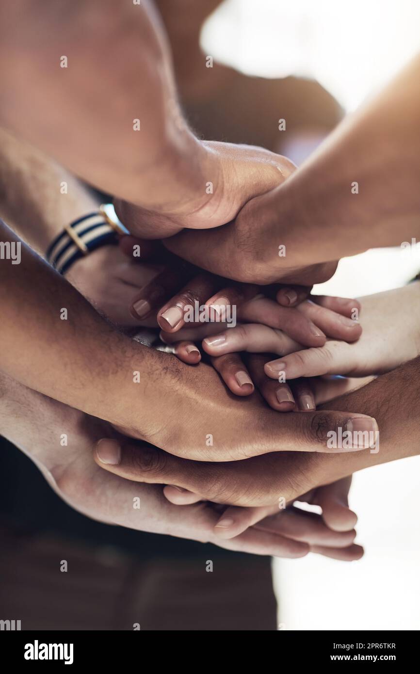 Were all connected. Cropped shot of a work group joining hands in solidarity. Stock Photo