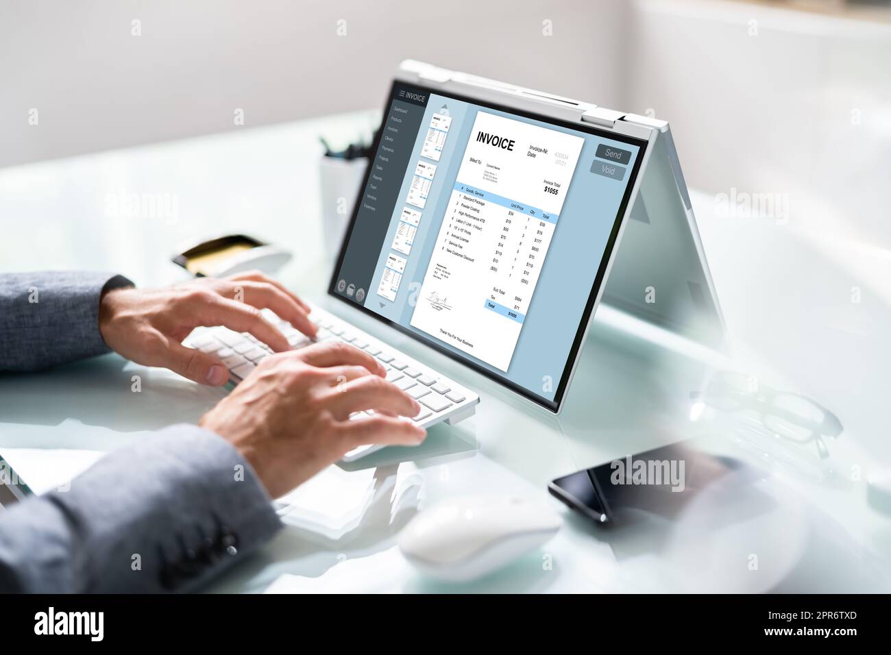 Businessperson Analyzing Invoice On Laptop Stock Photo
